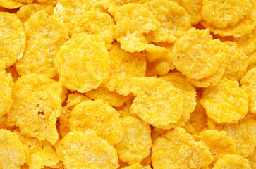 Yellow corn flakes background, texture, top view. Corn flakes for morning breakfast, background, texture, top view. Background and texture of yellow corn flakes, top view.