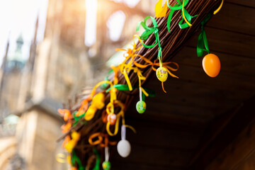 Multicolored bright easter eggs decoration hanged on paper ribbons on wooden house roof against old...