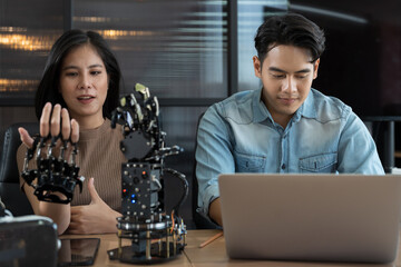 Young male and female working with AI robot arm system project in workshop. Male engineer using...