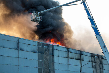 Firefighters extinguish a fire in an industrial building with the help of a fire truck