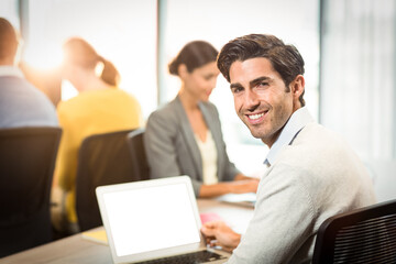 Businessman holding laptop with colleague in background
