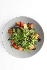 Salad with baked eggplant. Baked eggplant with arugula and tomatoes and cucumbers. Plate on a white background.Photos for the menu.Vertical photo.