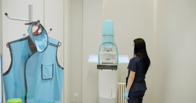 Female doctor examines and prepares the diagnostic machine in the hospital. Diagnosis of breast cancer. Medical breast x-ray for women. Cancer Prevention Routine in Hospital Room.