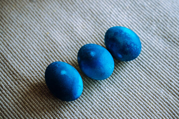 Diagonal of three blue dyed easter eggs on woven background