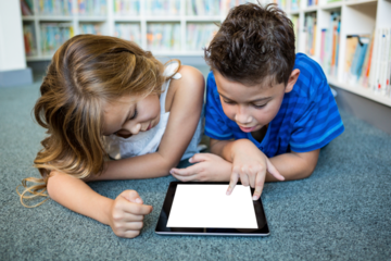 Children using digital tablet while lying on floor