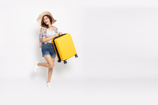 Happy Young Asian woman traveler in summer outfit holding suitcase bag isolated on white background, Tourist in summer and holidays vacation concept