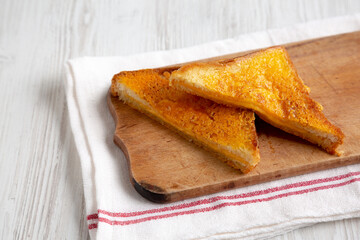 Homemade Inside-Out Grilled Cheese Sandwich on a rustic wooden board, side view.