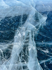 The natural texture of winter ice with white bubbles and cracks on a frozen lake. Abstract background of ice and cracks on the surface of frozen Lake Baikal
