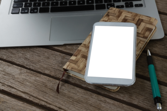 Laptop, mobile phone, dairy and pen on wooden plank