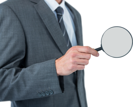 Mid section of businessman holding magnifying glass