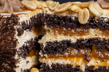 a piece of chocolate cake with caramel and peanuts