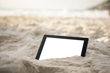 Digital tablet kept on sand at beach