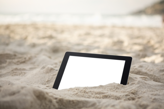 Digital tablet kept on sand at beach