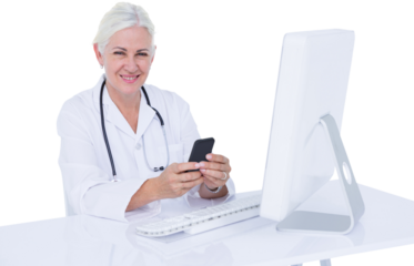 Smiling female doctor holding mobile phone at computer desk