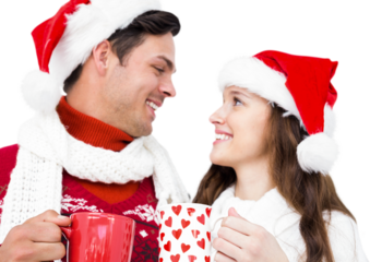 Happy couple with santa hats holding mug