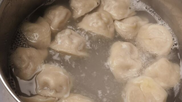 Boiling homemade meat dumplings, closeup. Cooking Russian traditional meal