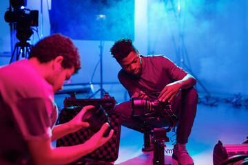 Two professional photographers setting cameras before shooting while working in studio