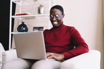 Happy black man browsing laptop