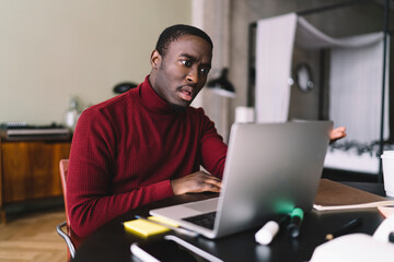Surprised male freelancer working on laptop