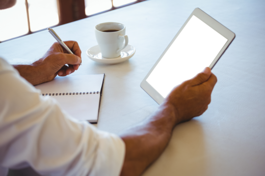 Mature man holding digital tablet while sitting at cafe