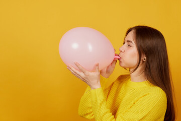 young girl inflates a pink balloon