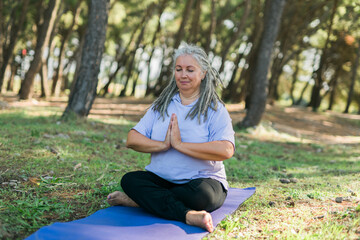 Obraz premium Mindful senior woman portrait with dreadlocks meditating on nature close up copy space - wellness and yoga practice
