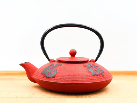 Red cast iron teapot with oriental characters.