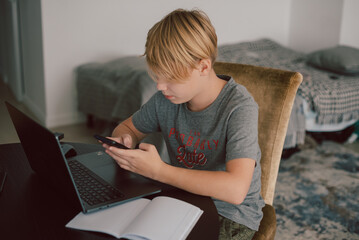 young boy studies using computer and smartphone