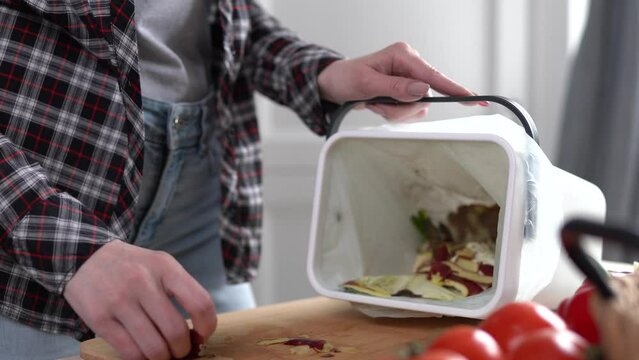 House wife cooking dinner and composting organic food waster. Woman throwing food peels into bokashi composter bin for recycling