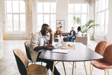 Black man sitting at table with laptop while looking at screen