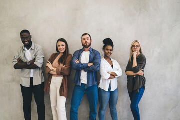 Group of multiethnic friends standing near gray wall