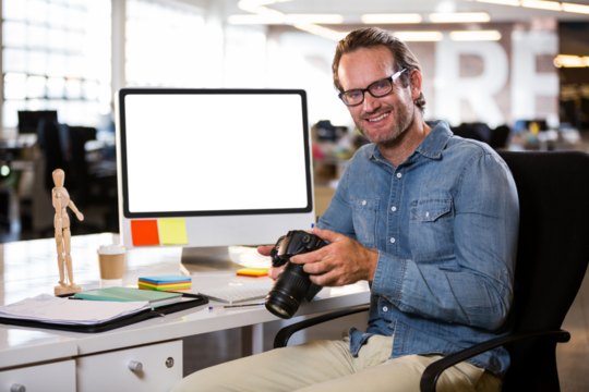 Man holding digital camera in office
