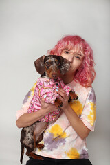 A girl with pink hair is smiling with a dog. friends Marble dachshund. White background