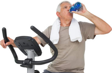 Senior man drinking water on stationary bike