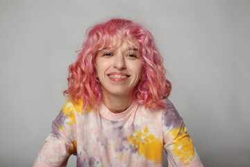 A girl with pink hair is smiling. White background