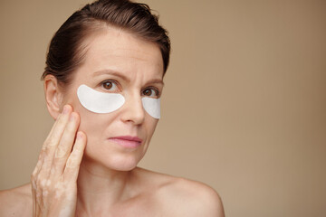 Mature woman applying undereye patches in the morning to get rid of puffiness