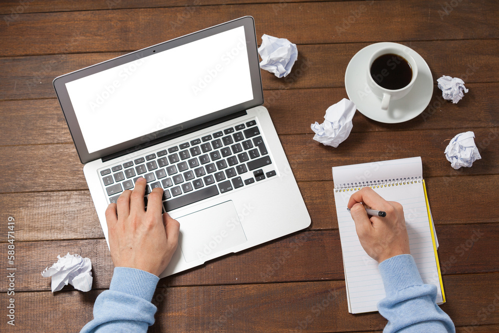 Poster man using laptop while writing on notepad