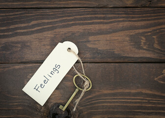 Feelings concept.  Gold key  with a label on wood table.