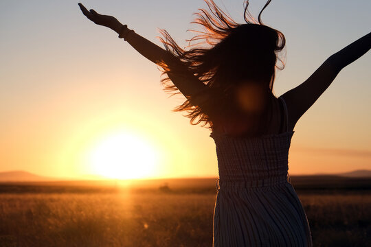 silhouette of a girl with her hair blowing in the wind at sunset