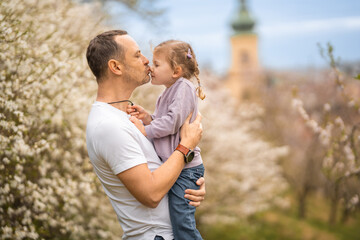 Father and daughter having a fun together under a blooming tree in spring park Petrin in Prague, Europe