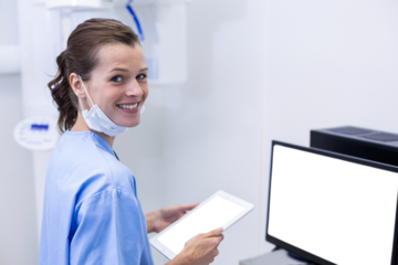 Smiling dental assistant holding digital tablet