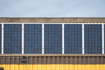 Solar power panels on the facade of a yellow warehouse.