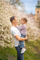 Father and daughter having a fun together under a blooming tree in spring park Petrin in Prague, Europe