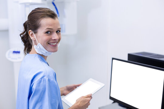 Smiling dental assistant holding digital tablet