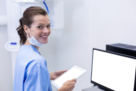 Smiling dental assistant holding digital tablet - Powered by Adobe
