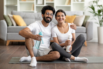 Sporty indian couple exercising together at home and posing at camera