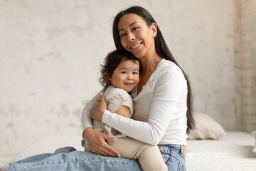 Korean Mother Hugging Holding Toddler Baby Daughter Sitting At Home