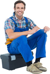 Plumber writing notes while sitting on tool box