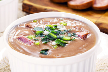 Brazilian bean broth, homemade bean soup served warm in winter, with ingredients in the background, macro photography