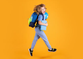Kid jump and enjoy school. Full length body of cheerful school child jumping running back to school isolated over yellow background.
